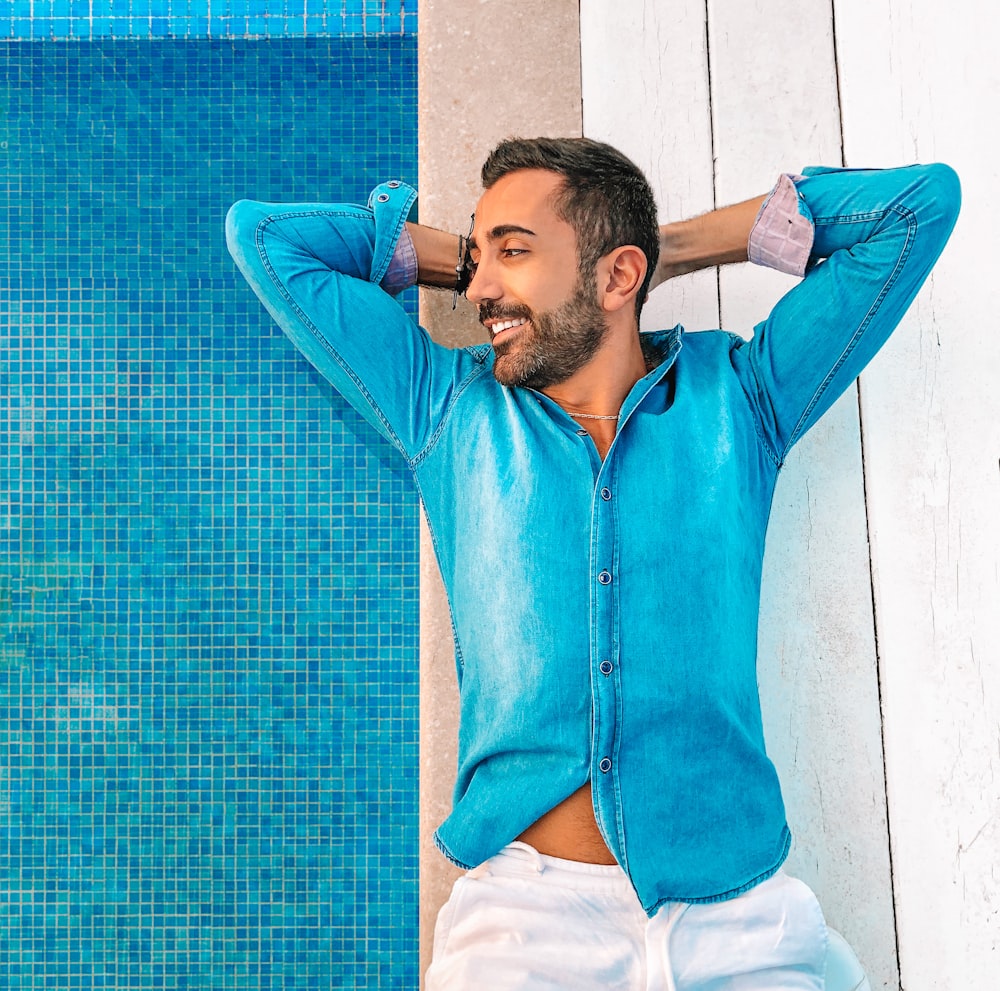 man in blue zip up jacket leaning on blue wall