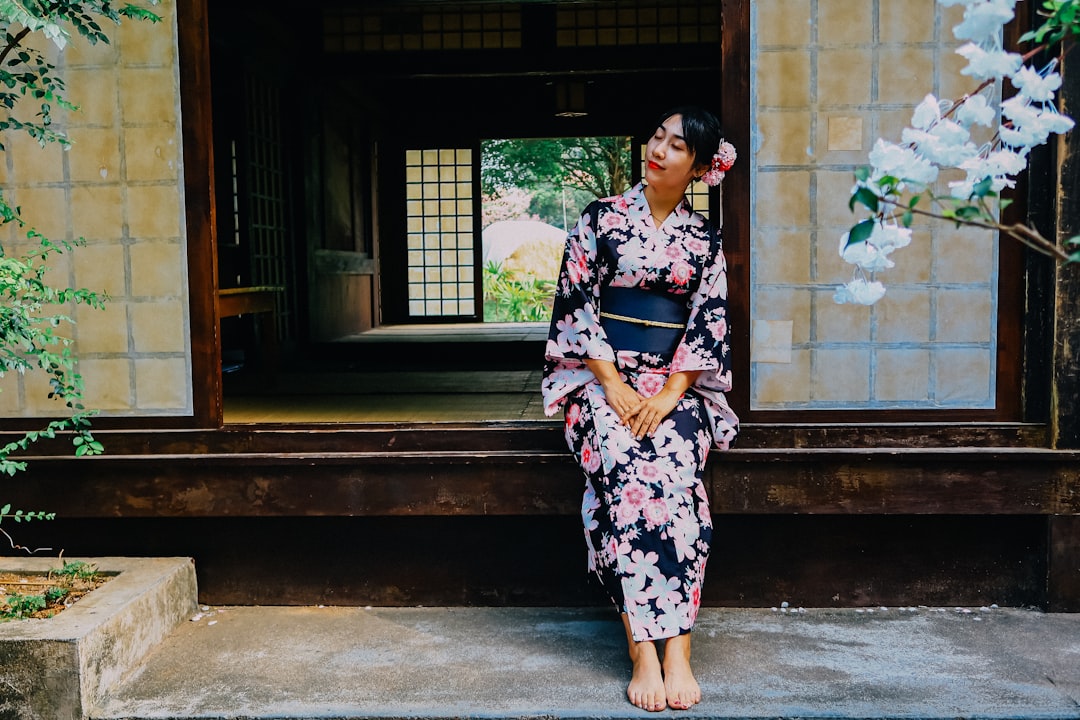 woman in blue white and red floral kimono standing on sidewalk during daytime