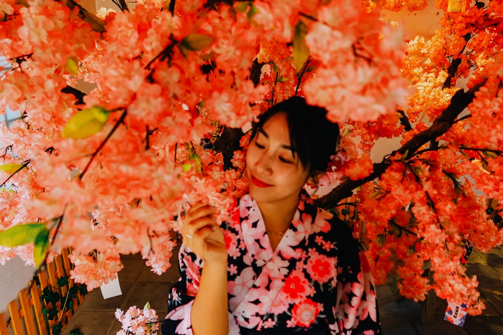 woman in red and white floral dress standing under orange leaves