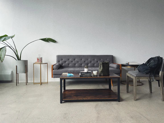 A minimalist living room featuring a nordlys side table with a small plant and a book.