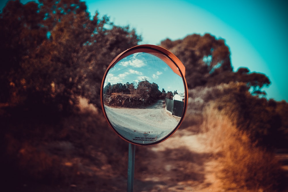 round mirror reflecting trees during daytime