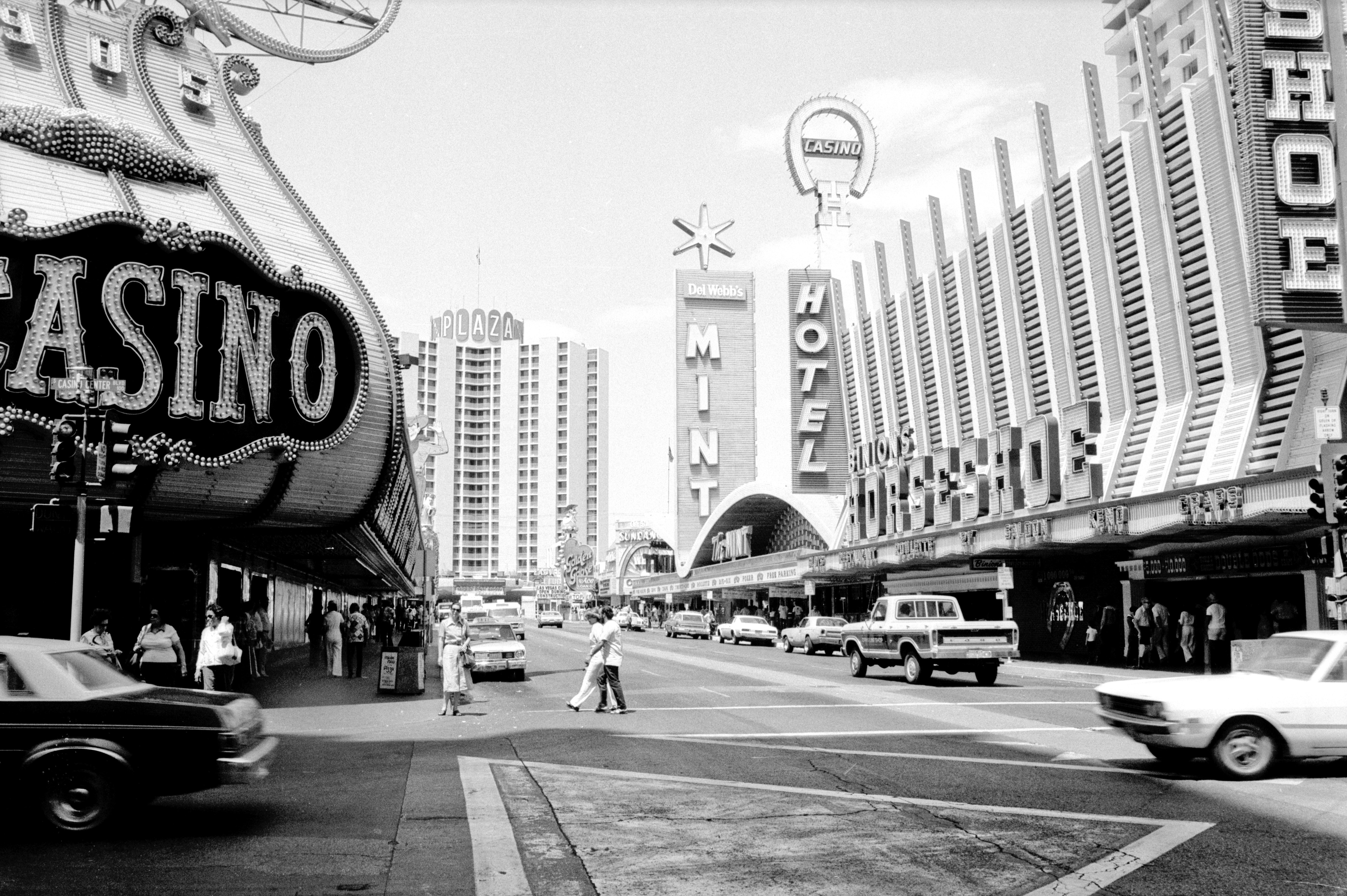 grayscale photo of people walking on pedestrian lane near city buildings