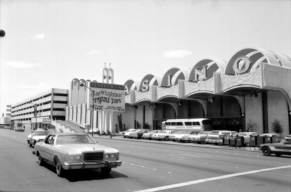 grayscale photo of cars on road near building