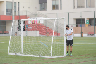 woman in white shirt and black shorts standing on green field