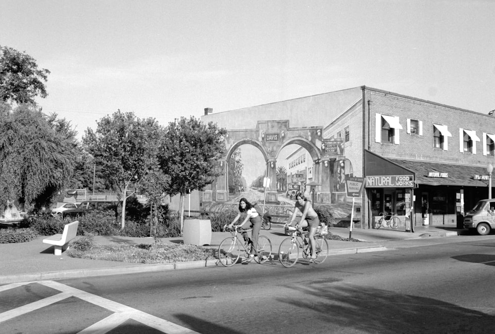 grayscale photo of man riding bicycle on road