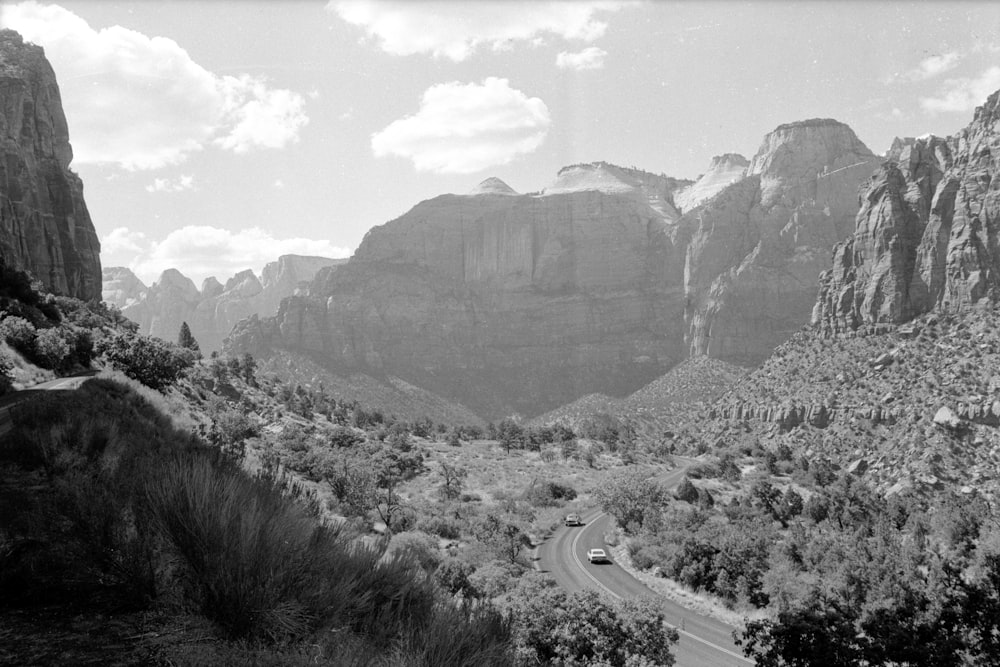 grayscale photo of road between mountains