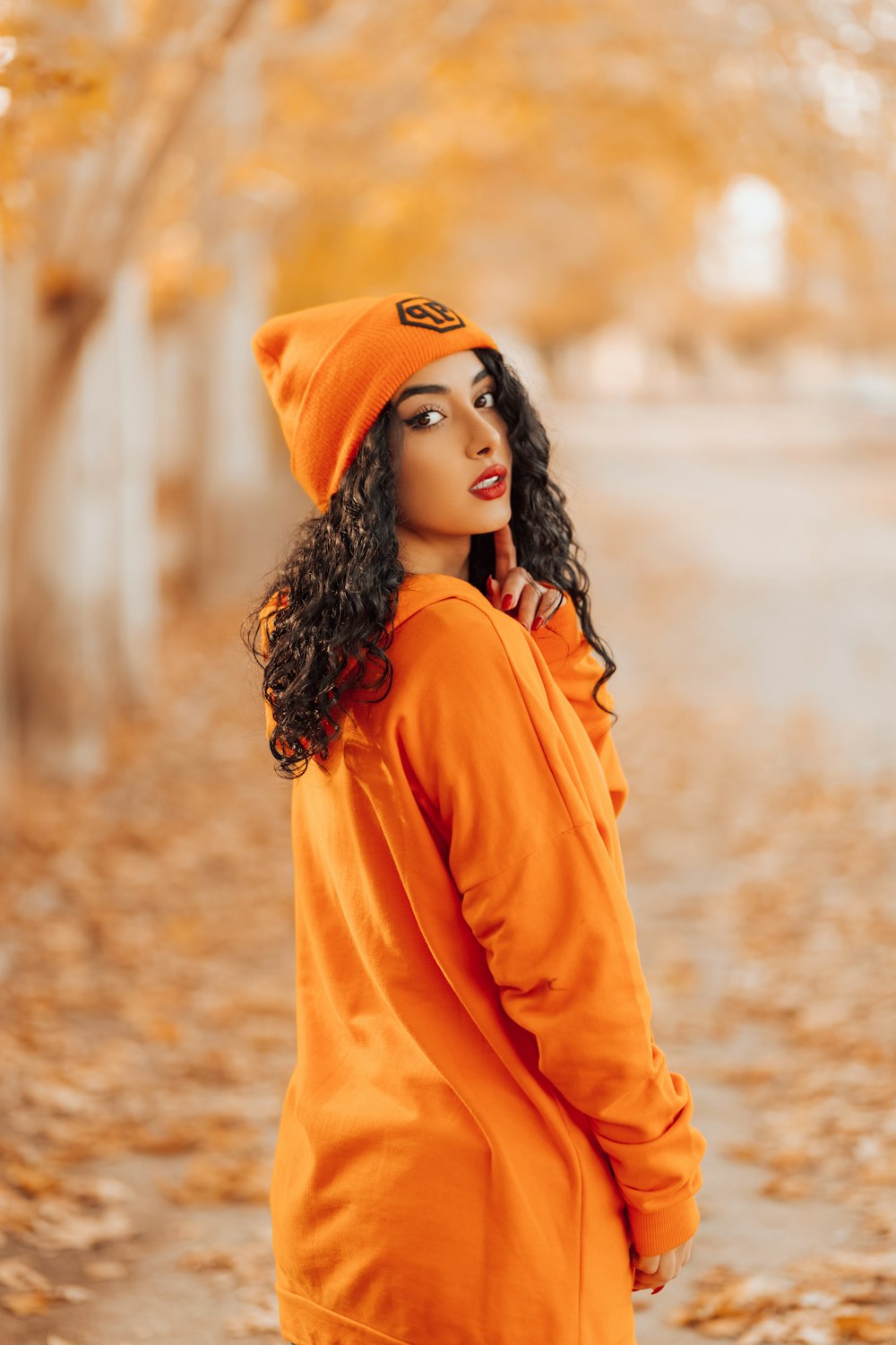 woman in orange hoodie standing on brown soil during daytime