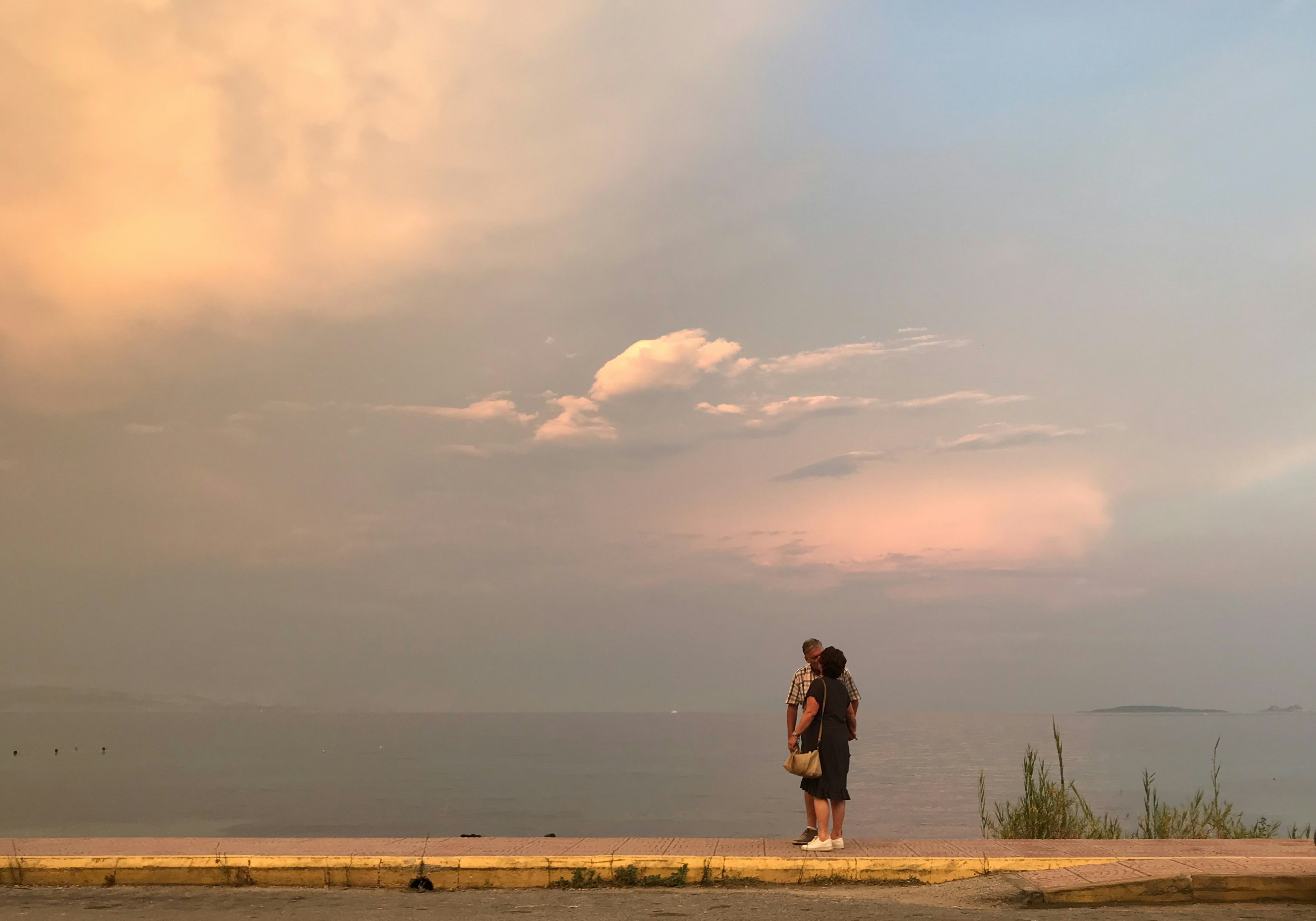 man and woman standing on brown sand near body of water during daytime