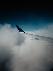 white and blue airplane wing under blue sky during daytime