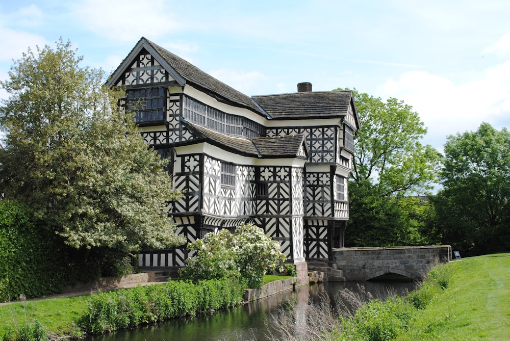 white and black house near green trees and river during daytime