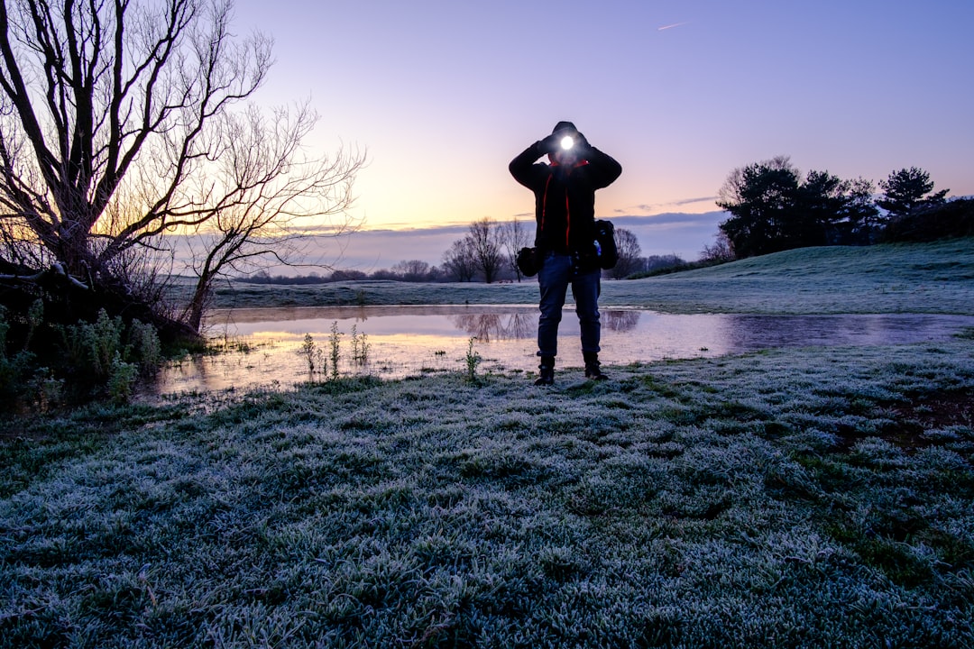 person in black jacket standing on green grass field during daytime