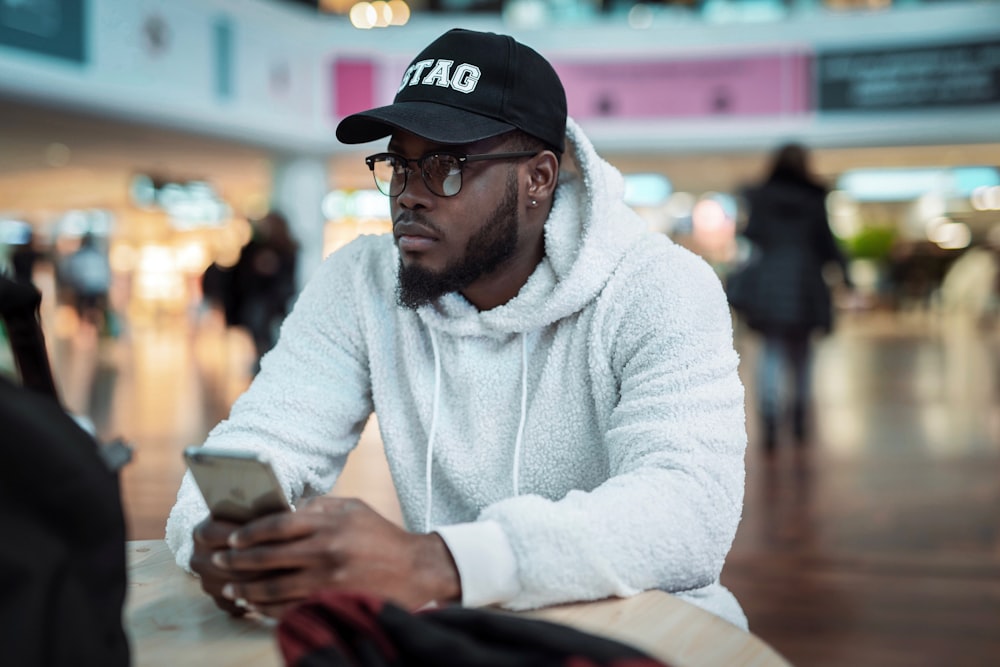 man in white sweater wearing black and white cap