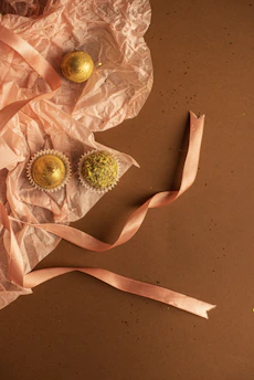 Elegant wedding chocolate favors wrapped in blush pink and gold, arranged delicately on ivory linen.