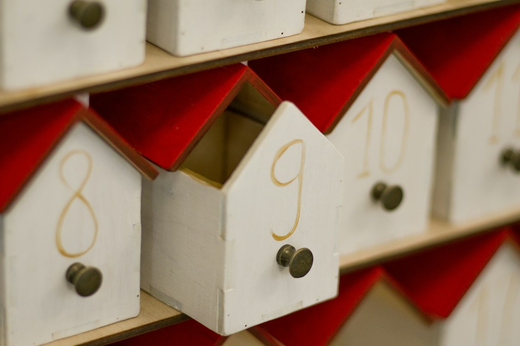 Calendrier de l'Avent en bois en forme de petites maisons blanches à toit rouge, tiroirs numérotés 8, 9 et 10