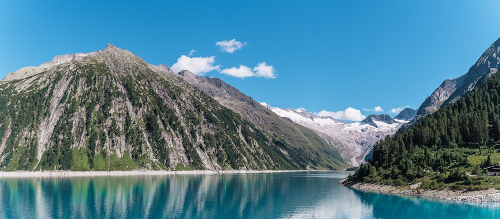 boat on lake near mountain under blue sky during daytime