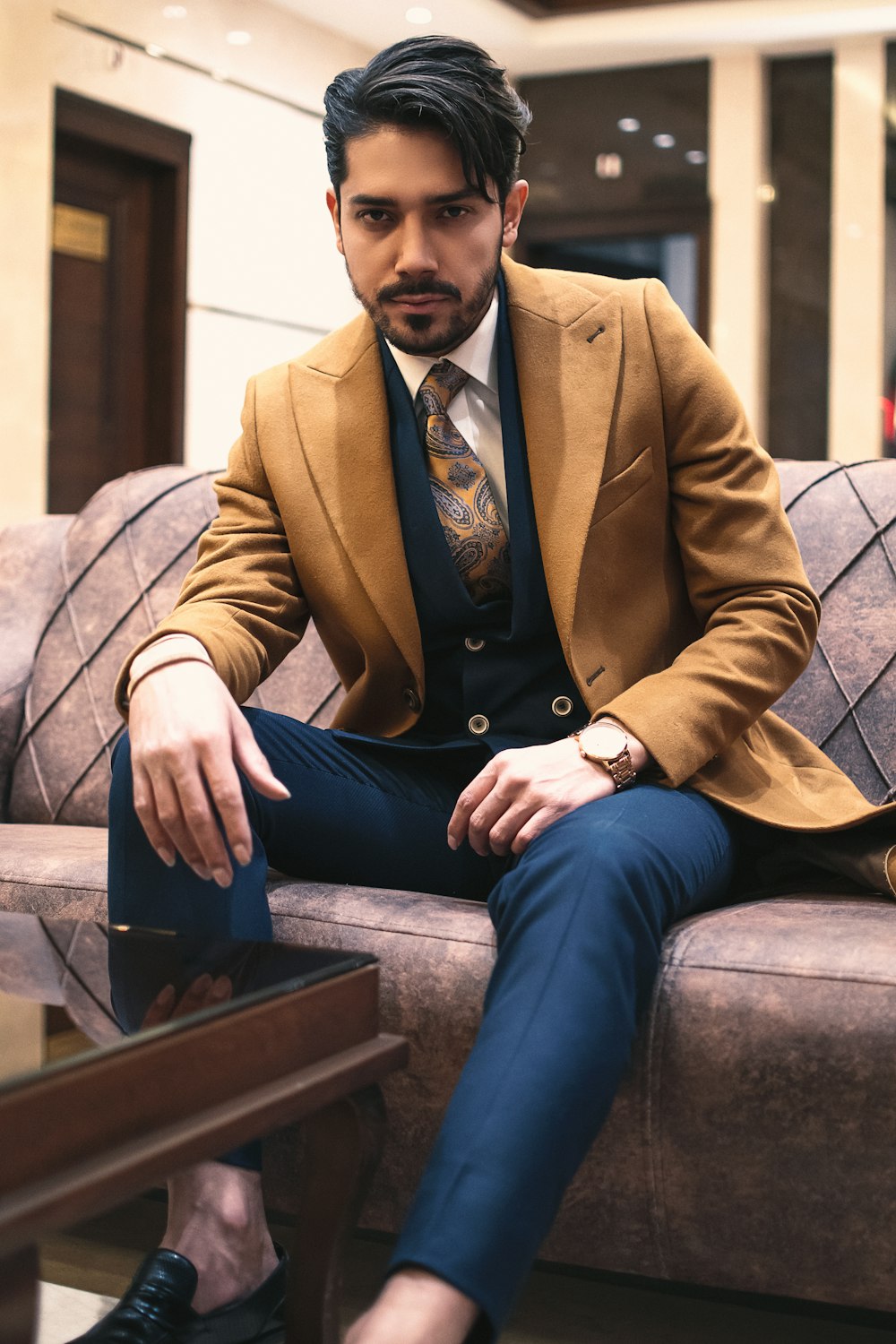 Foto Hombre con chaqueta de traje marrón y jeans azules sentado en un banco  de madera marrón – Imagen Iraní gratis en Unsplash