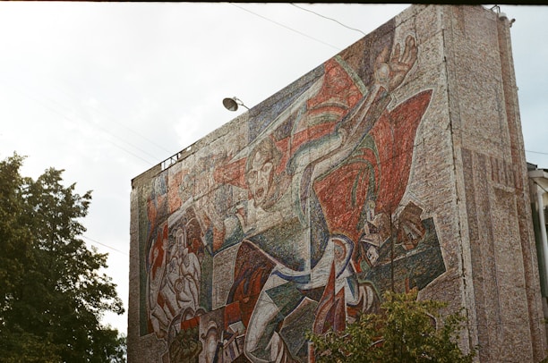 A large, colorful mural on an urban wall featuring dynamic shapes and expressive figures.