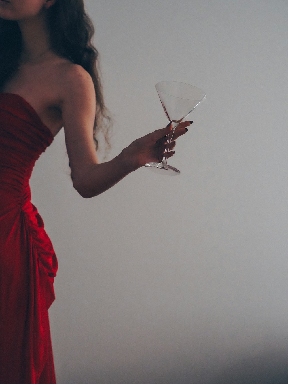 mulher no vestido vermelho do tubo que segura o copo do vinho