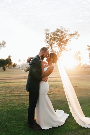 A bride and groom sharing a joyful moment under soft golden sunlight during their wedding ceremony.