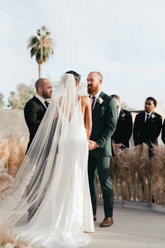 bride and groom standing on grass field during daytime