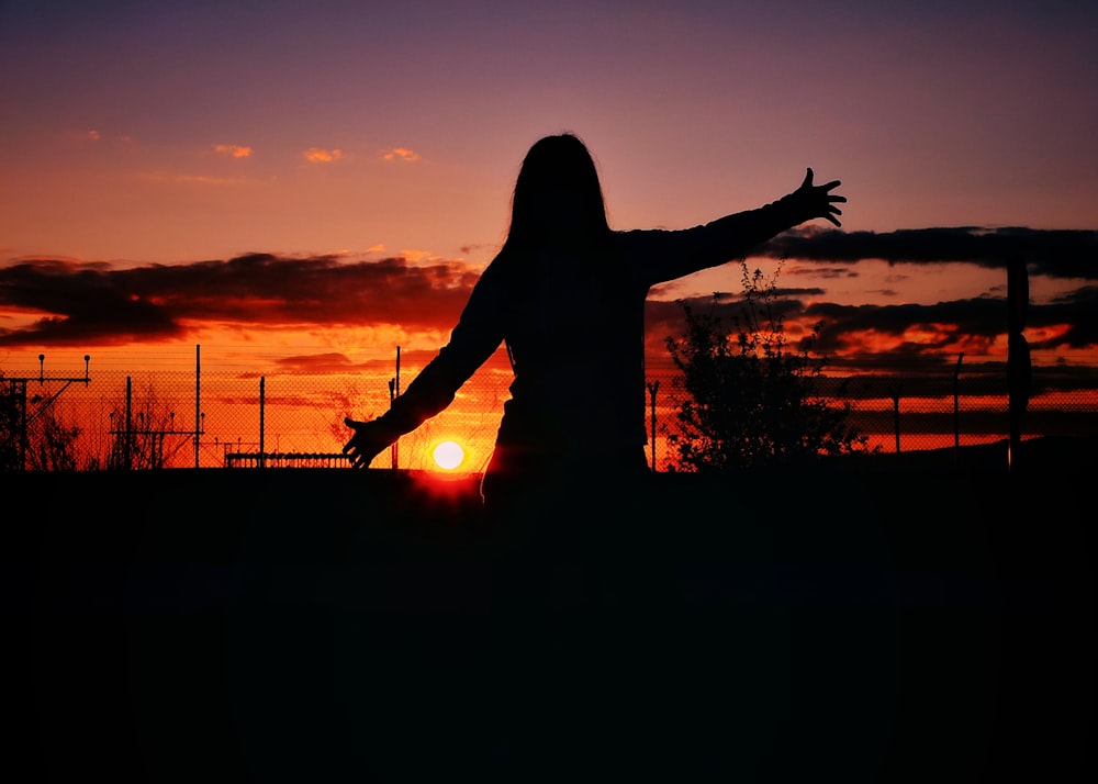 Silueta de mujer de pie durante la puesta del sol