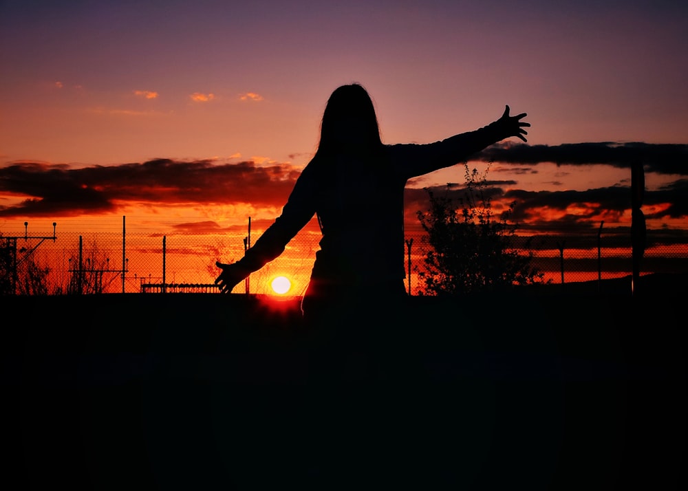 Silhouette einer Frau, die bei Sonnenuntergang steht