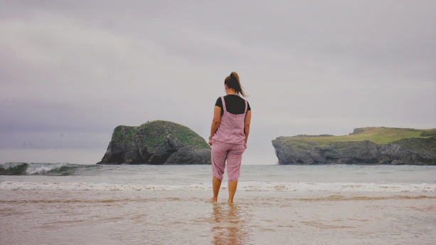 woman in pink dress standing on beach during daytime