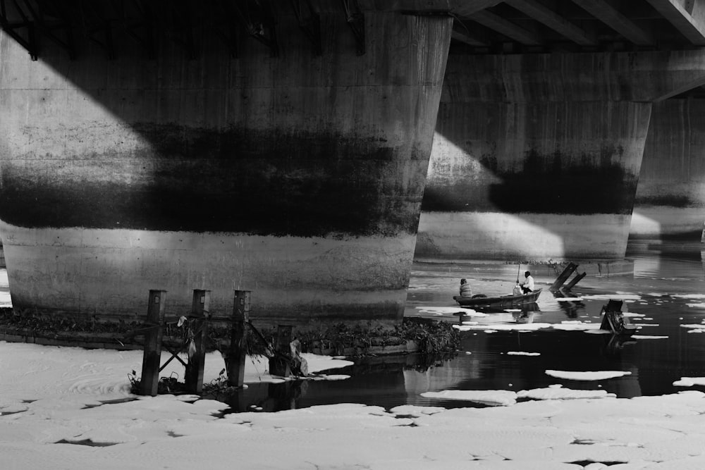 Graustufenfoto von Menschen am Strand in der Nähe von Bridge