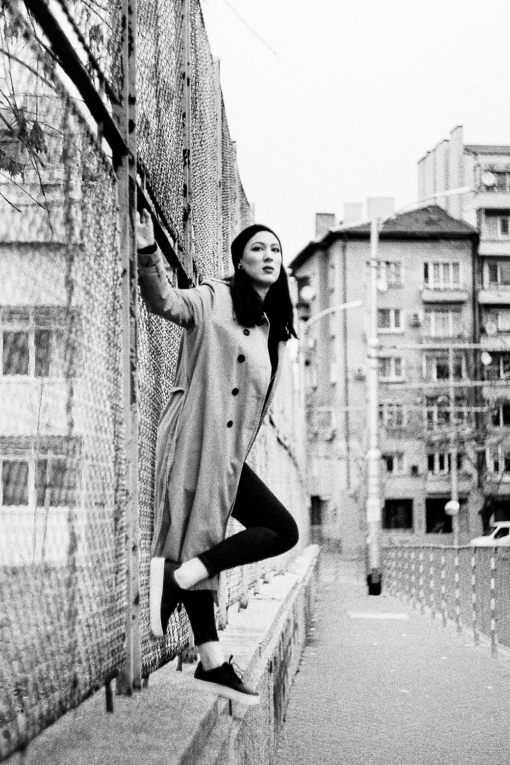 woman in coat and pants standing on sidewalk