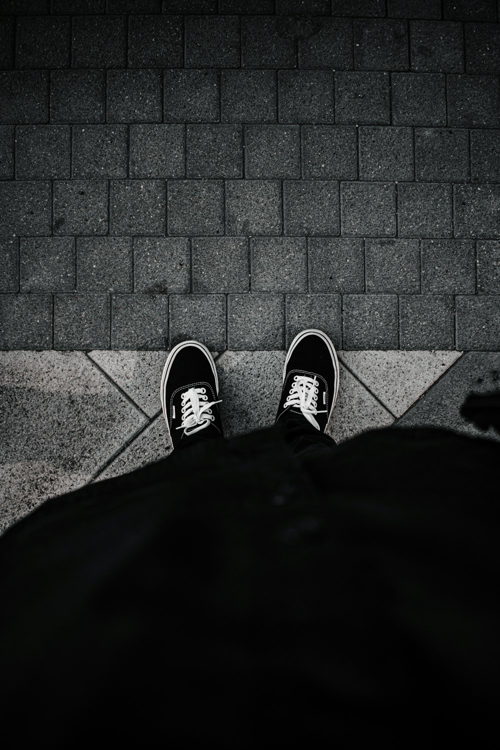 person in black pants wearing black and white sneakers