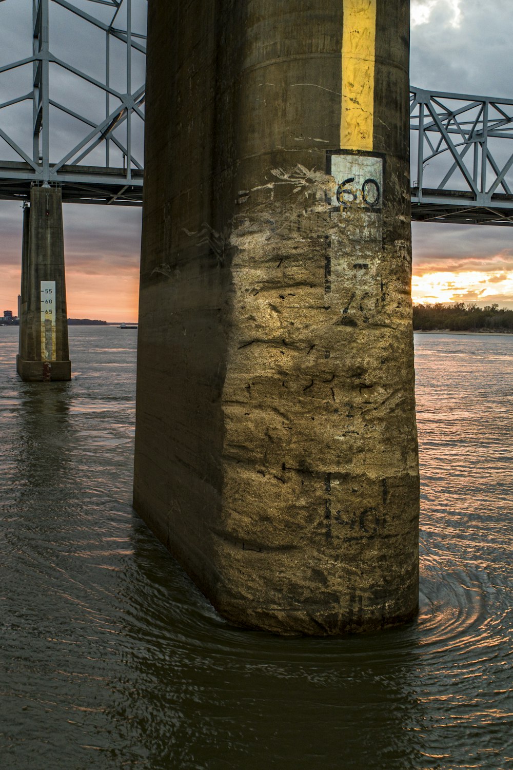 brown concrete post on water during sunset