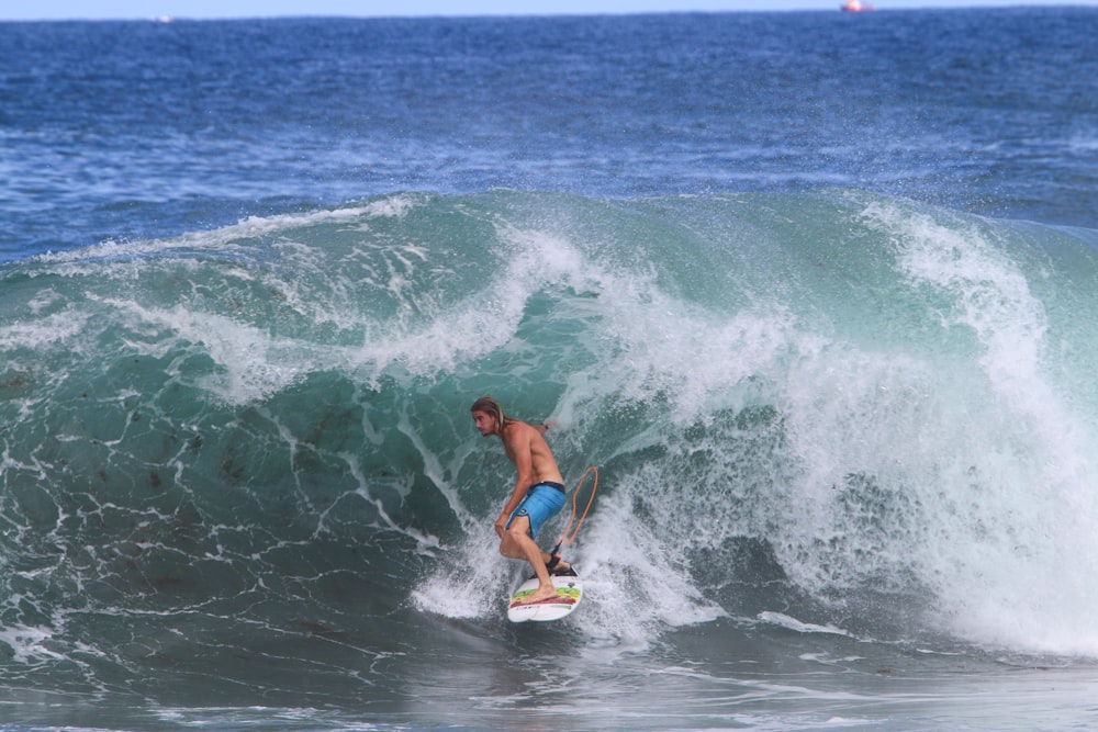 Mujer en bikini azul surfeando en las olas del mar durante el día