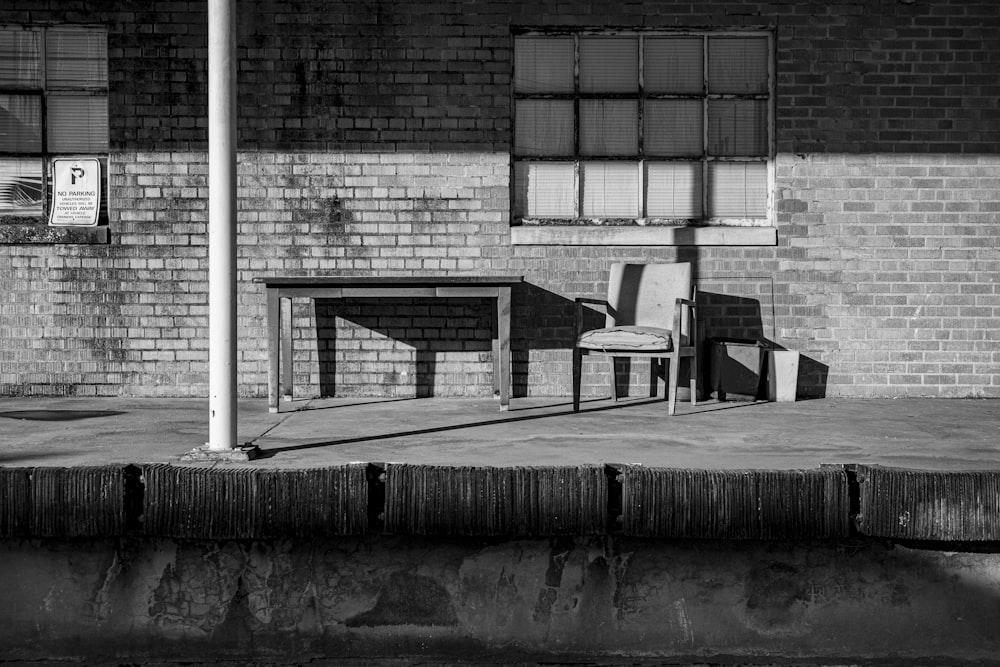 grayscale photo of wooden bench near building