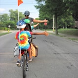 Children wearing bright helmets riding bikes on a sunny neighborhood street.