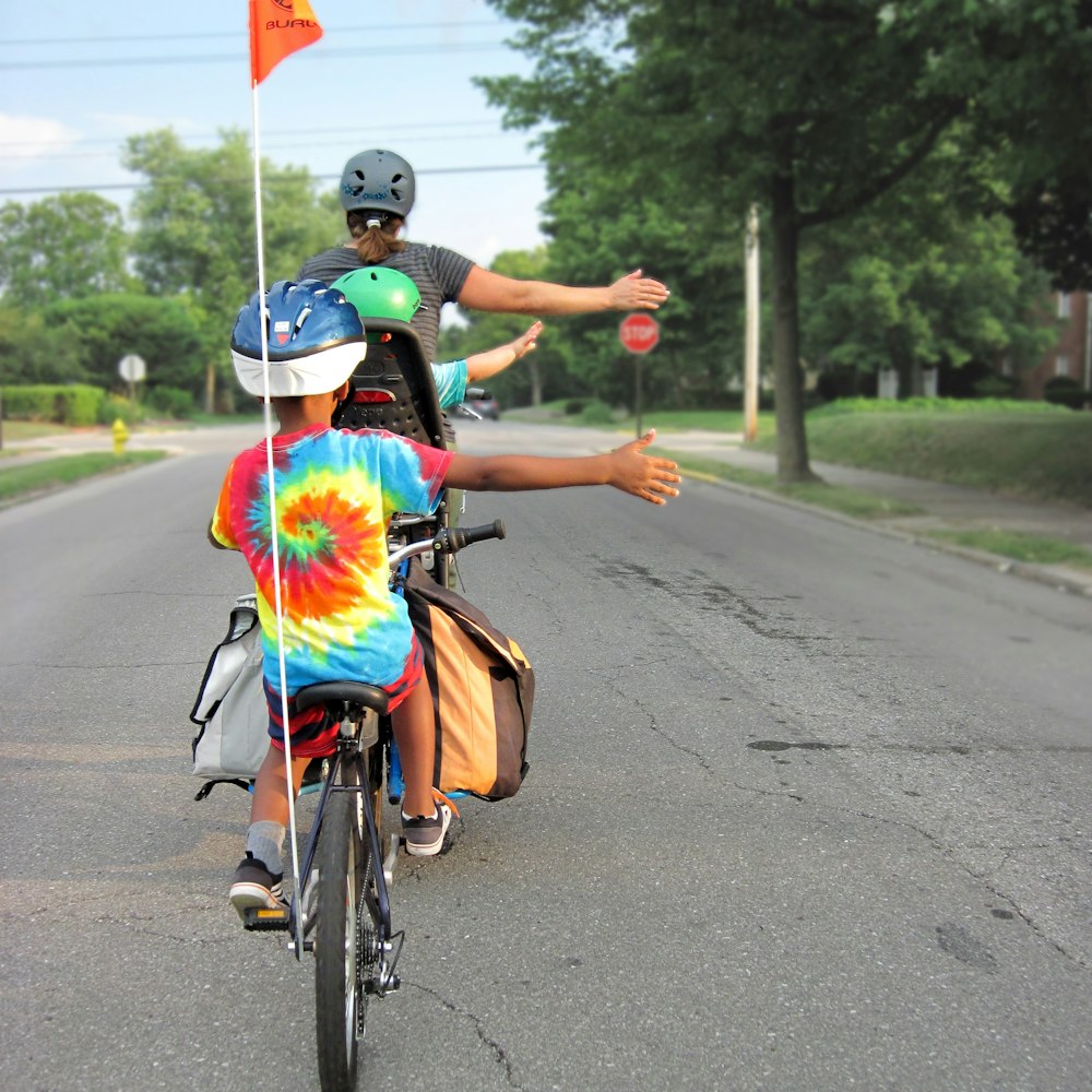 Mujer en vestido azul y rojo montando en bicicleta en el camino durante el día