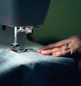 Portrait of an artisan sewing delicate fabric in a softly lit workshop.