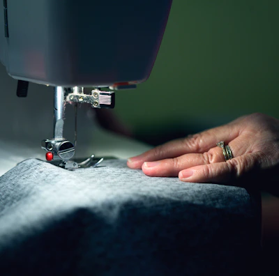 Portrait of an artisan sewing delicate fabric in a softly lit workshop.