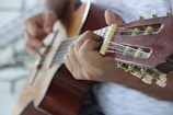 person playing brown acoustic guitar