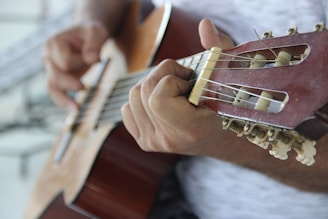 person playing brown acoustic guitar