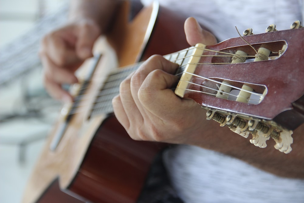 Persona tocando la guitarra acústica marrón