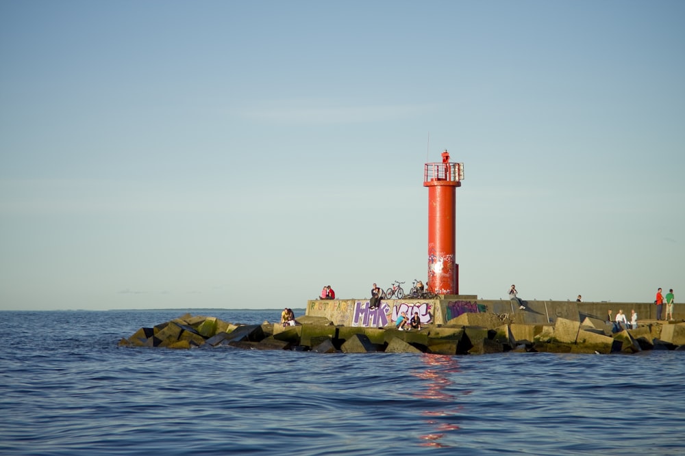 red and white lighthouse on green grass field near body of water during daytime