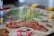 A close-up of a board game map featuring colorful plastic soldier figures placed on different regions. The game pieces include red, yellow, green, and black soldiers, with several dice nearby. The map appears to represent different continents with labeled areas.