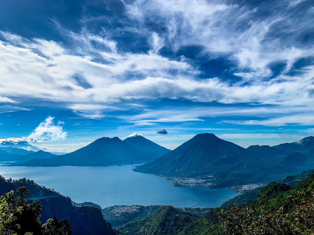 montañas verdes bajo nubes blancas y cielo azul durante el día