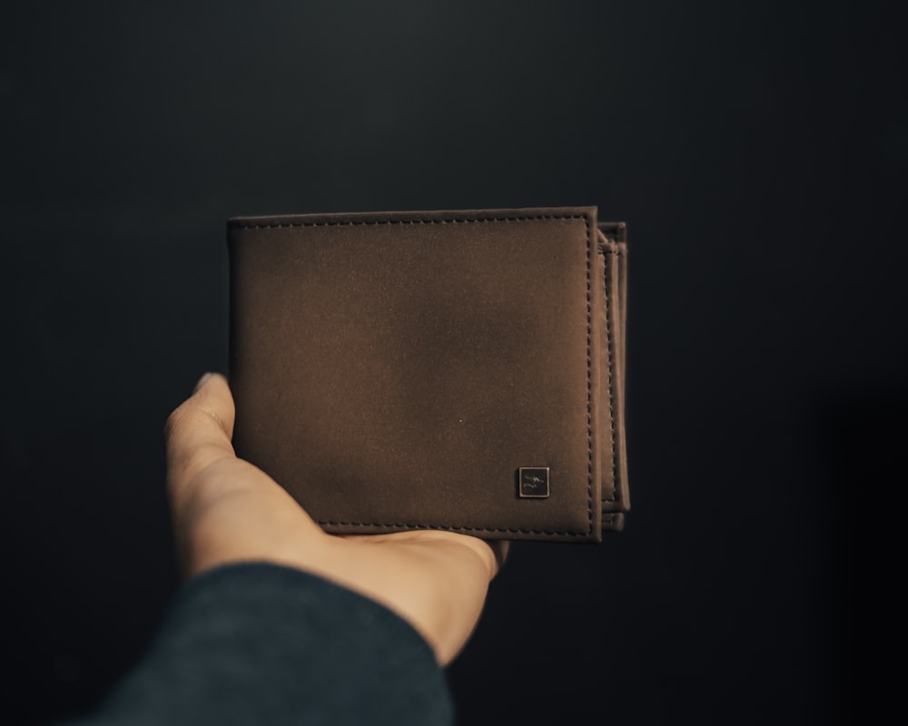 茶色の革の二つ折り財布を持っている人