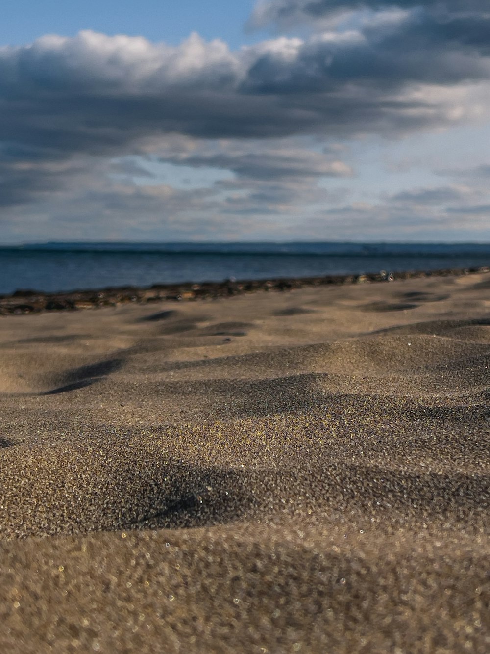 brown sand near body of water under blue sky during daytime