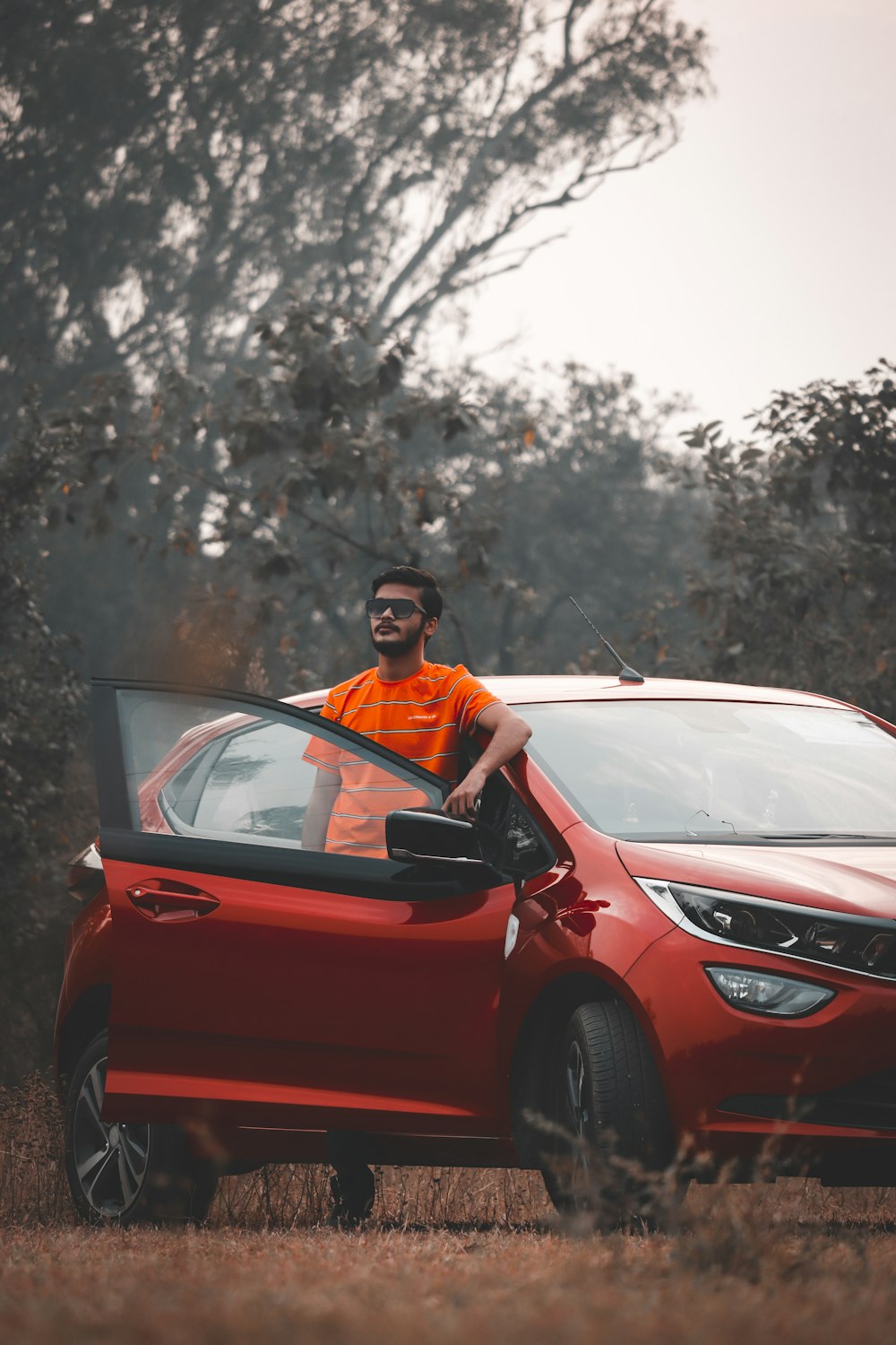 man in orange shirt driving red car