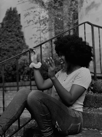 A joyful person clipping a hey-me charm onto their backpack before heading out for the day.