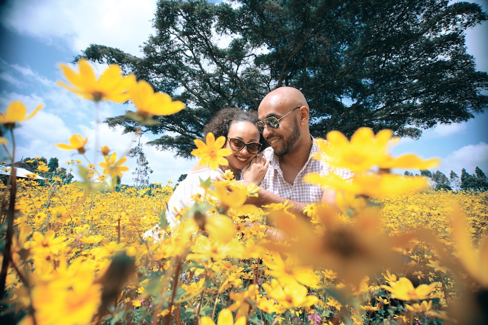 man and woman kissing under yellow flower tree during daytime