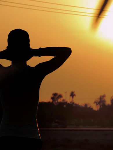 silhouette of man raising his hands during sunset