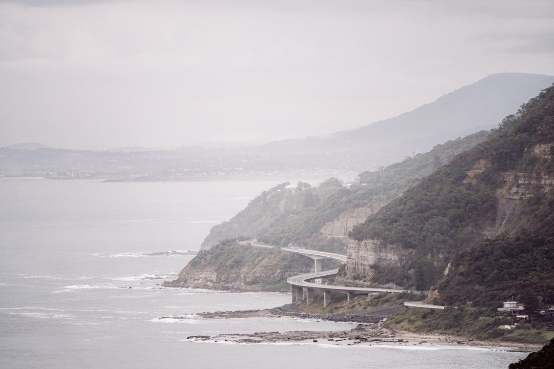 white bridge on body of water near mountain during daytime